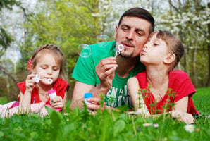 A dad blowing bubbles with his kids on Father's Day